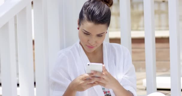 Mujer soltera sentada cerca de valla usando teléfono inteligente — Vídeos de Stock