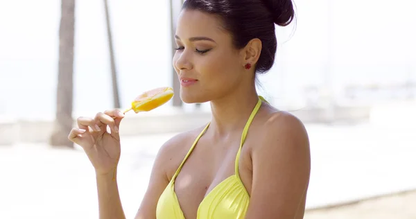 Woman in bathing suit eating mango ice pop — Stockfoto