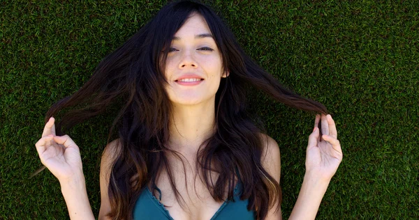 Hübsche Frau mit langen braunen Haaren liegt im Gras — Stockfoto