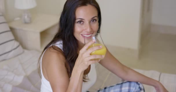 Lächelnde gesunde junge Frau trinkt Orangensaft — Stockvideo