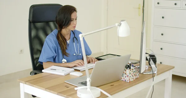 Женщина врач сидя печатая в офисе — стоковое фото