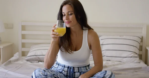 Mulher desfrutando de vidro de suco de laranja — Fotografia de Stock