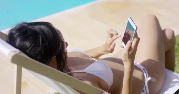 Женщина просматривает мобильный телефон под летним солнцем — стоковое видео