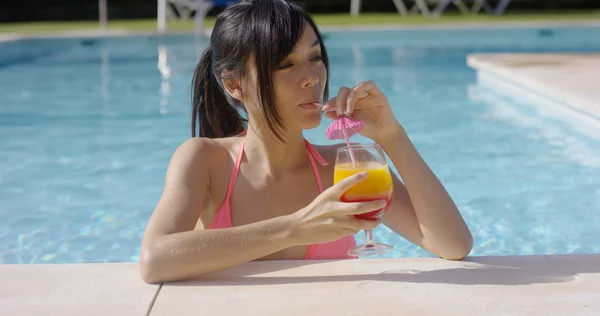 Femme sirotant un cocktail dans la piscine — Photo