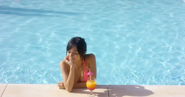 Woman at pool edge with drink — Stockfoto