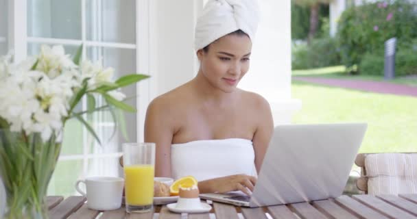 Mujer usando el ordenador portátil mientras desayuna — Vídeos de Stock