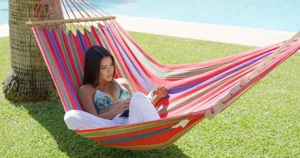 Frau im Bikini liest Buch in Hängematte — Stockfoto