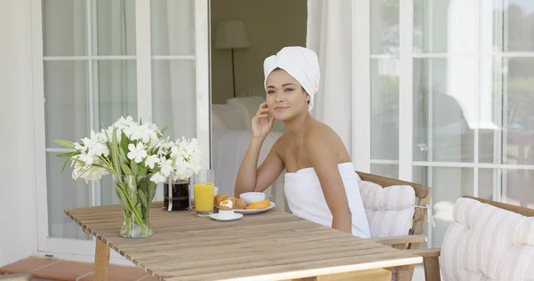 Woman wrapped in towel sitting at table — Stock Photo, Image