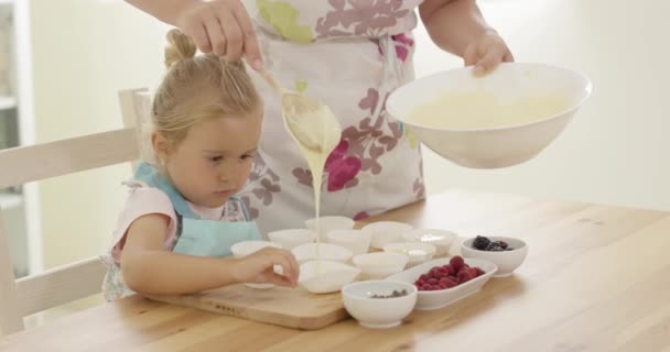 Parent pouring muffin batter into holders — Stock Video