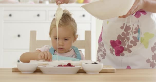 Parent pouring muffin batter into holders — Stock Video