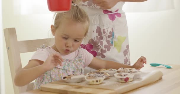 Ребенок заинтересован в сахаре, падающем на кексы — стоковое видео