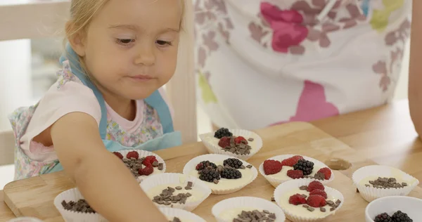 Menina colocando bagas em muffins — Fotografia de Stock