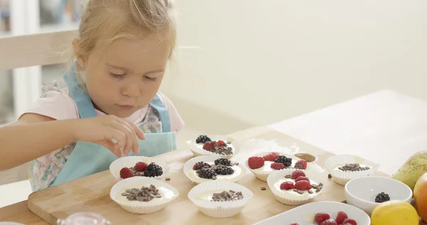 Menina colocando bagas em muffins — Fotografia de Stock