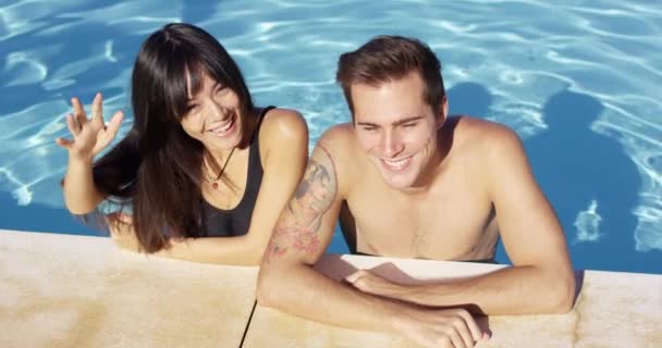 Smiling couple standing in clear pool wave — Stock Video