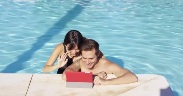 Couple in swimming pool using digital device — Stock Video