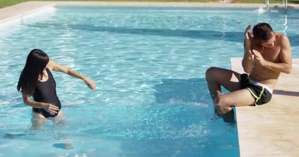 Novia chapoteo novio en piscina — Vídeos de Stock
