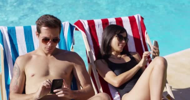 Pareja usando teléfonos en la piscina — Vídeos de Stock