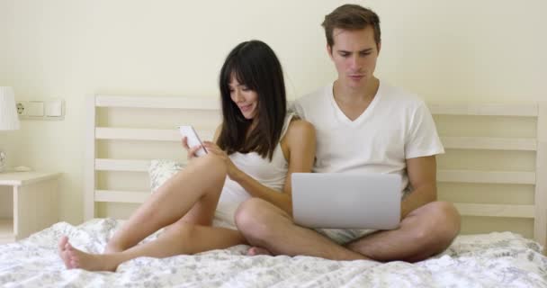 Пара сидить разом у ліжку з ноутбуком — стокове відео