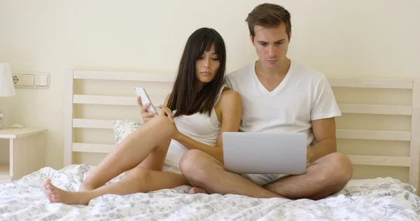 Serious couple sitting together in bed — Stock Photo, Image