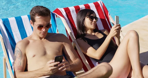 Pareja usando teléfonos en la piscina —  Fotos de Stock