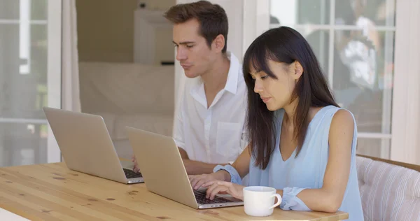 Paar sitzt mit Computern am Tisch — Stockfoto