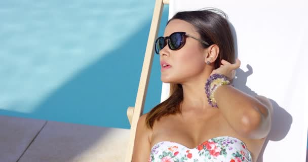 Mulher tomando banho de sol à beira da piscina na cadeira deck — Vídeo de Stock