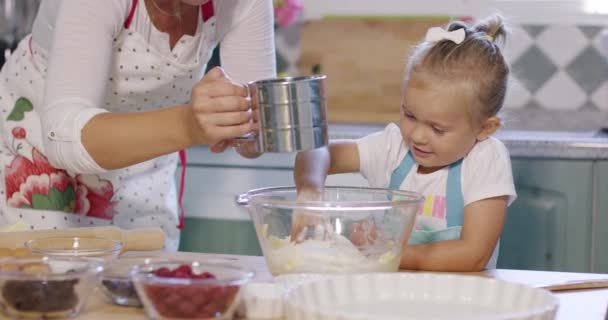 Roztomilá holčička pomáhat matce upéct dortík — Stock video