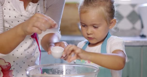 Linda niña añadiendo sal a una mezcla de hornear — Vídeos de Stock