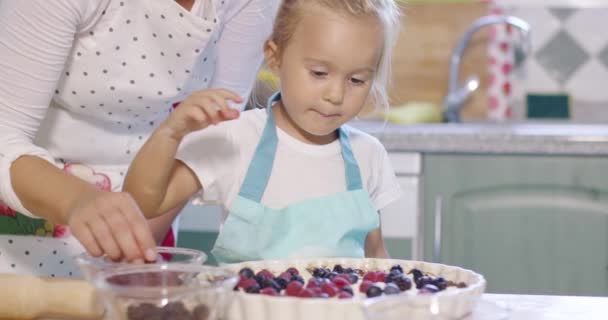 Mutter und Tochter fügen frische Beeren zu einem Kuchen hinzu — Stockvideo
