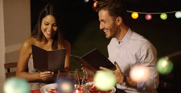 Giovani coppie che ridono mentre attraversano il menu — Foto Stock