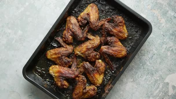 Alitas de pollo a la parrilla en especias en bandeja para hornear de metal negro sobre mesa de piedra. Vista superior — Vídeos de Stock