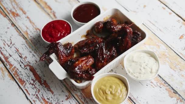 Chicken Wings in dicker Barbecue-Sauce mit verschiedenen Dips. Serviert auf weißer gusseiserner Schüssel — Stockvideo