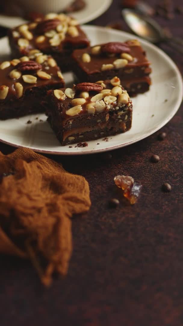 Los trozos cuadrados de delicioso pastel de caramelo con cacahuetes y nueces brasileñas servidas con café con leche — Vídeos de Stock