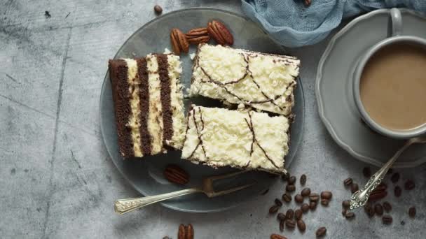 Smaklig lagrad tårta beströdd med vit choklad. Serveras med kopp kaffe på en grå betong — Stockvideo