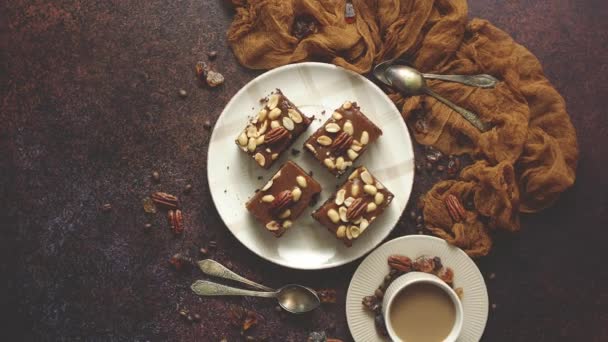 Квадратні шматочки смачного карамельного торта з арахісом та бразильськими горіхами, що подаються з молочною кавою — стокове відео
