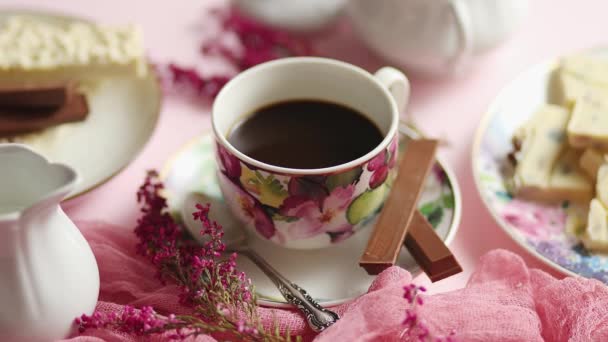 Delicioso postre sobre fondo rosa. Café caliente o chocolate negro con chocolate blanco — Vídeo de stock