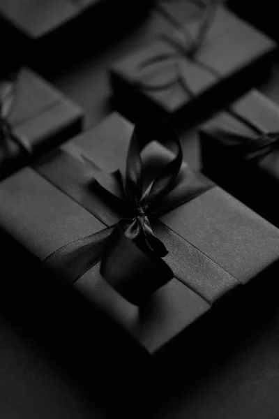 Black Christmas Konzept. Nahaufnahme von eleganten, schwarz matt verpackten Geschenken mit Schleife. — Stockfoto