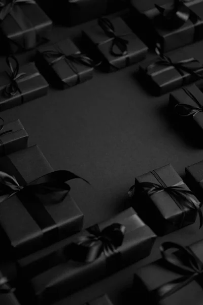 Cajas Regalos dispuestas envueltas en papel negro con cinta negra sobre fondo negro. Concepto de Navidad —  Fotos de Stock