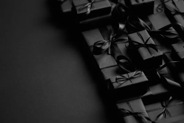 Una pila de varios tamaños de regalos en caja negra colocados en la pila. Concepto de Navidad. — Foto de Stock