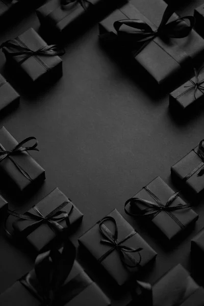 Cajas Regalos dispuestas envueltas en papel negro con cinta negra sobre fondo negro. Concepto de Navidad —  Fotos de Stock