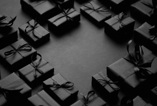 Cajas Regalos dispuestas envueltas en papel negro con cinta negra sobre fondo negro. Concepto de Navidad —  Fotos de Stock