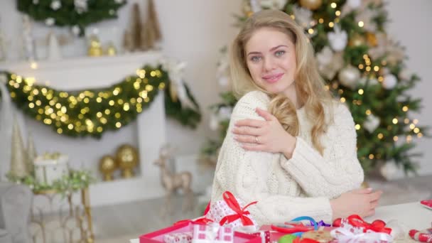 Χριστουγεννιάτικο πορτρέτο ενός χαμογελαστού ξανθού κοριτσιού σε ένα ζεστό ζεστό ζεστό πουλόβερ στο φόντο των Χριστουγέννων — Αρχείο Βίντεο