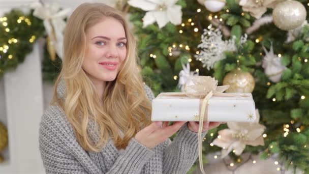 Χαμογελαστή ξανθιά γυναίκα που ποζάρει με χριστουγεννιάτικο κουτί δώρου — Αρχείο Βίντεο