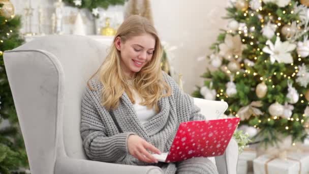 Retrato de mulher sorridente segurando laptop em suas voltas e trabalhando. Sentado em poltrona confortável — Vídeo de Stock