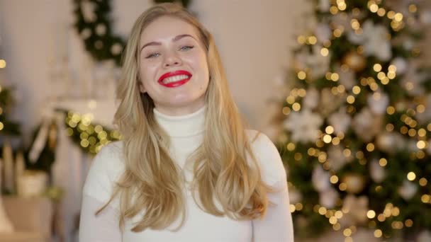 Noel ağacının önünde örgü kazak giyen şık, güler yüzlü bir kadın. — Stok video