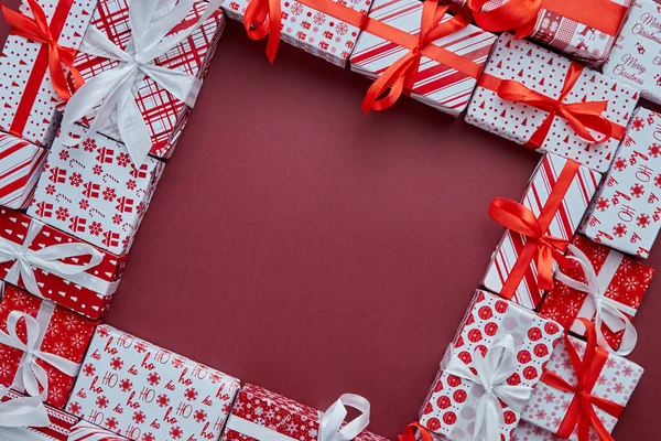 Geschenken dozen verpakt in kleurrijk feestelijk papier met op burgund achtergrond — Stockfoto