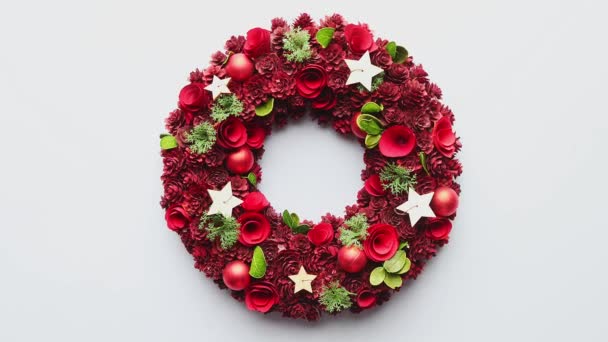 Top view of a large Christmas Wreath made with red ornaments placed on white plain background — Stock Video