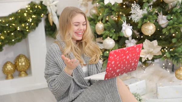 Ευτυχισμένη νεαρή γυναίκα που έχει βίντεο chat στο φορητό υπολογιστή στο χριστουγεννιάτικο διακοσμημένο σαλόνι — Φωτογραφία Αρχείου