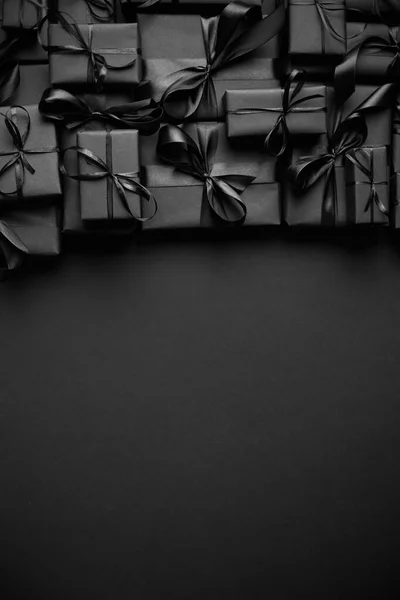 Una pila de varios tamaños de regalos en caja negra colocados en la pila. Concepto de Navidad. —  Fotos de Stock