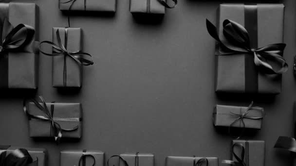 Geschenken dozen verpakt in zwart papier met zwart lint op zwarte achtergrond. Kerstconcept — Stockvideo